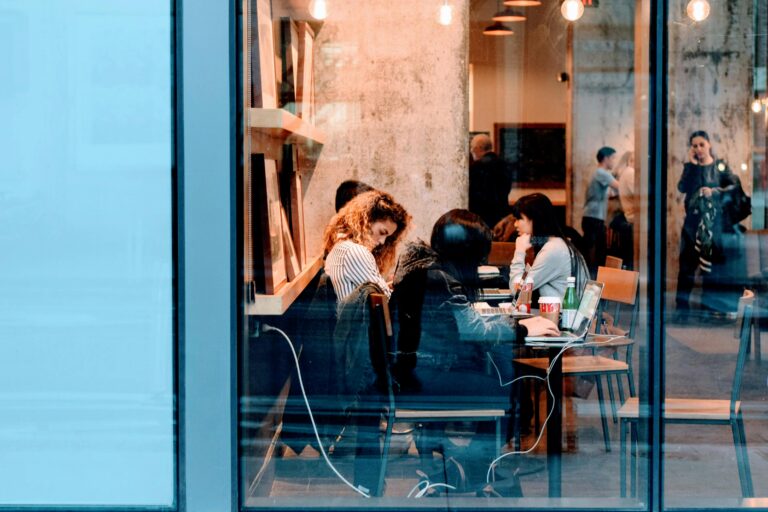 Group of adults working inside a stylish city cafe, showcasing modern work culture.